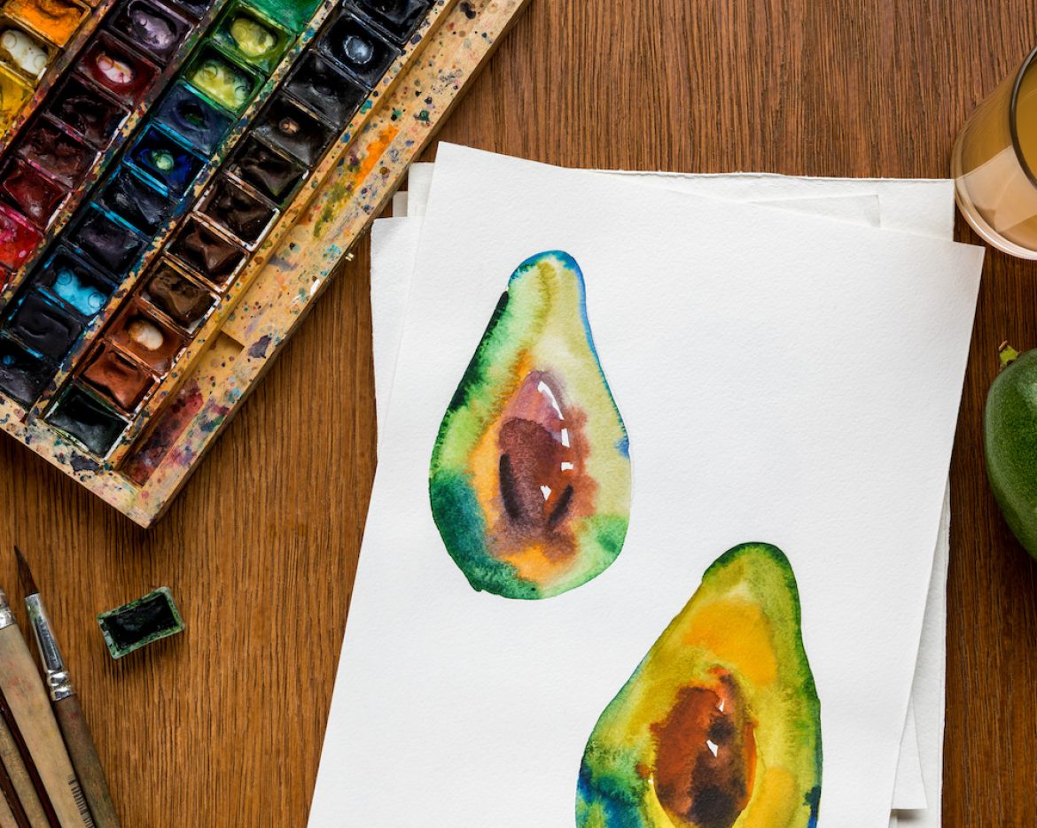 top view of colored paints, paintbrushes and drawing with avocado on wooden background